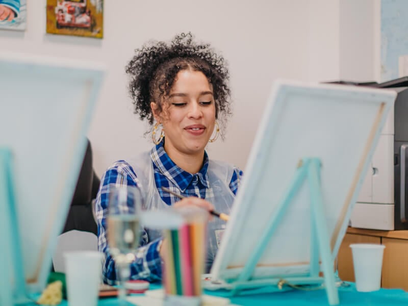 Woman smiling while she paints at a Brisbane workshop